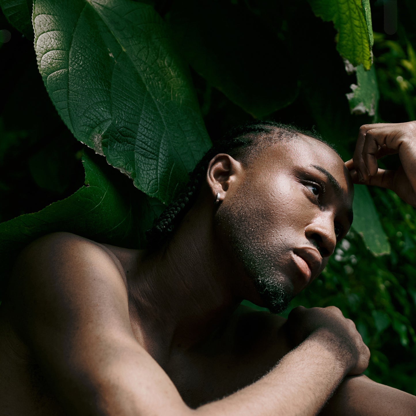 Muscular black man in jungle in thoughtful pose